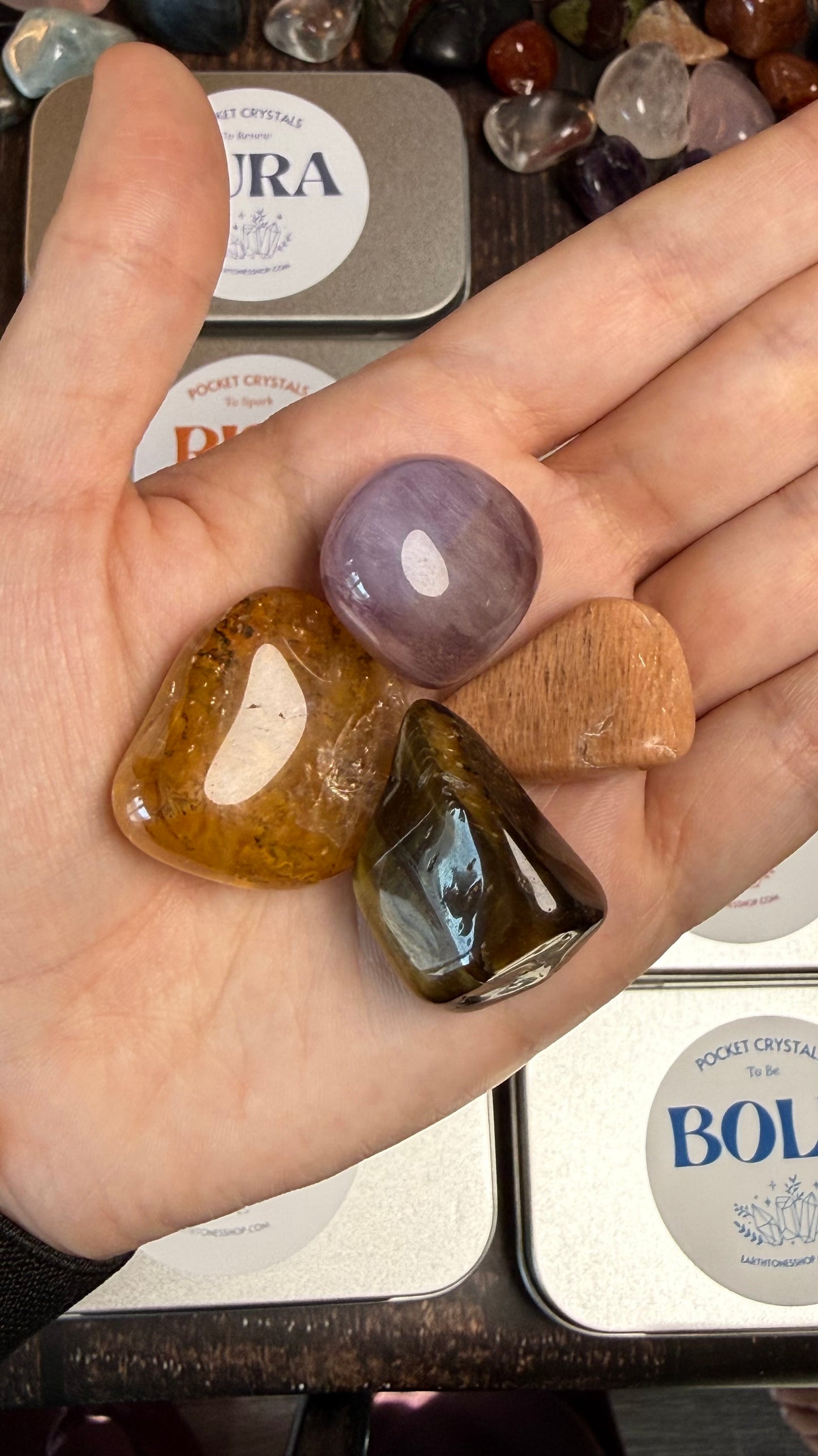 Golden Healer, Peach Moonstone, Tigers Eye, and Flourite  in palm of hand 
