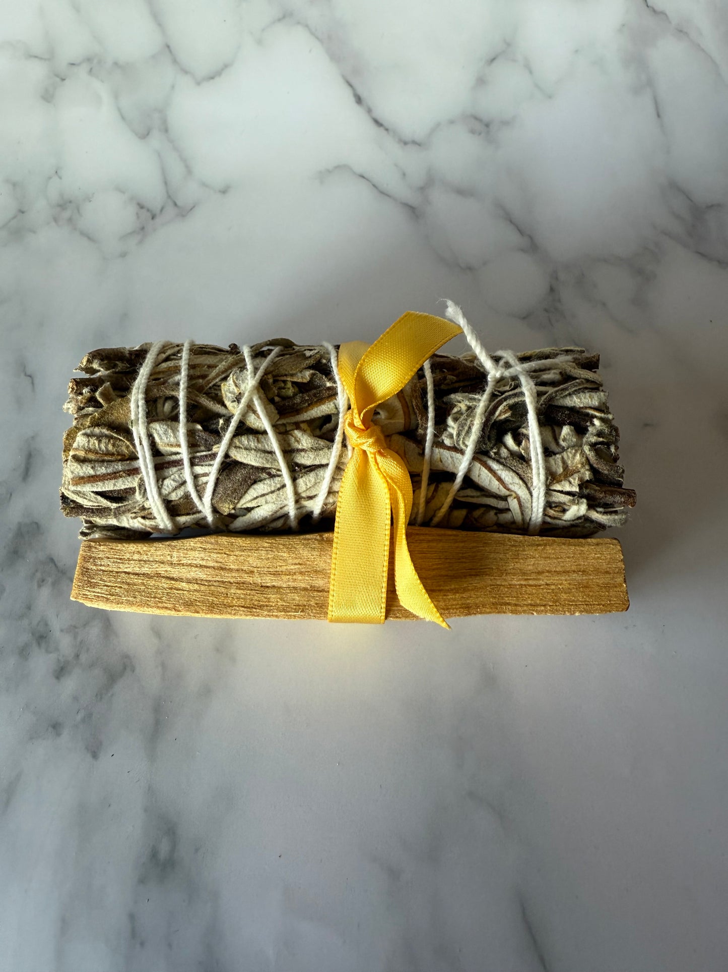 one bundle of palo and yerba wrapped with yellow ribbon on a marble surface