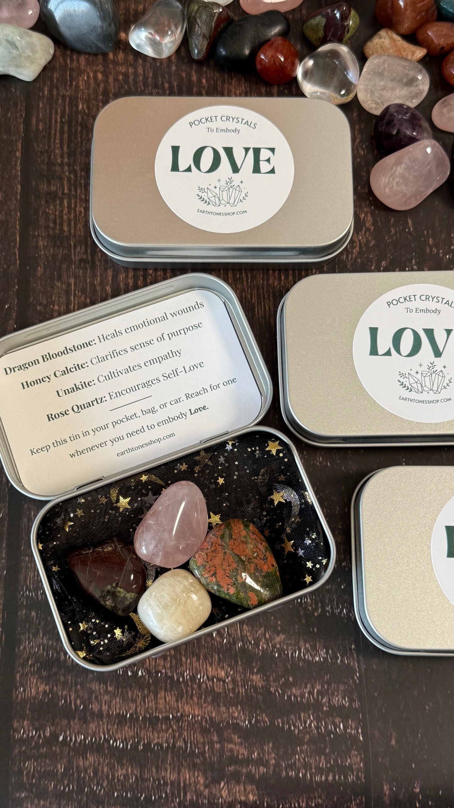 Dragon Bloodstone, Honey Calcite, Unakite and Rose quartz in tin on faux wood background 